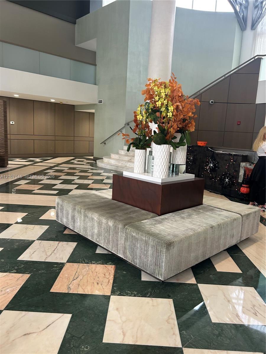 Grand foyer featuring geometric stone flooring in a contrasting diamond pattern, multi-level architectural design, and integrated panel wall detailing