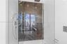 Walk-in shower featuring large-format dark stone tile accent wall, glass enclosure, ceiling-mounted rainfall showerhead, and integrated chrome handhel