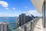 Expansive wraparound balcony featuring large-format tile flooring, a sleek glass railing, and a covered overhead soffit