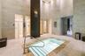 Soaking pool featuring a stone tile surround and metal grab rail, floor-to-ceiling stone wall cladding, and multiple private shower enclosures