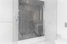Walk-in shower featuring large-format dark veined tile surround, frameless glass enclosure, handheld shower fixture, and linear drain