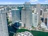 High-rise residential tower featuring a glass-curtain facade, prominent tiered architectural design, and water frontage along a canal