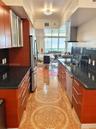 Kitchen featuring rich wood-finish cabinetry, dark stone countertops, patterned ceramic tile flooring, stainless steel appliances, and a modern stainl