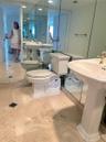 Bathroom featuring large-format light stone flooring with inlay accents, a pedestal sink with gold-tone hardware, and floor-to-ceiling wall mirrors