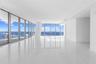 Floor-to-ceiling windows featuring panoramic water scenery, polished stone-finish flooring, and a structural column
