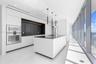 Modern kitchen featuring flat-panel cabinetry, a central island with a solid surface countertop, built-in stainless steel appliances, floor-to-ceiling