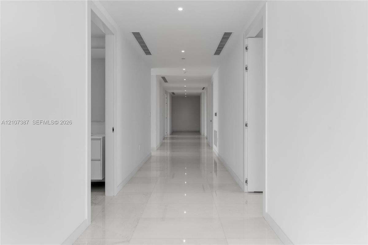Hallway featuring polished tile flooring, recessed ceiling lighting, and integrated linear fixtures