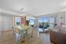Open-concept living space featuring wood-finish flooring, floor-to-ceiling glass sliding doors, built-in media cabinetry with high-gloss finishes, and