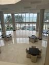 Double-height floor-to-ceiling windows, polished tile flooring, wood-finish flooring accents, structural cylindrical columns, and metal orb pendant li