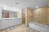 Double vanity with rectangular sinks, expansive wall-to-wall mirror, tiled soaking tub with glass partition, and separate walk-in shower featuring nat