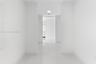 Interior corridor featuring polished stone-finish tile flooring, clean white walls, and recessed ceiling lighting