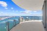 Curved balcony featuring tile flooring, glass panel railings, and panoramic coastal and urban scenery