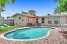 In-ground pool with a curved edge, surrounded by a brick paver patio and a grass lawn enclosed by a wood privacy fence