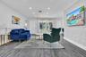 Open-concept living space featuring wood-finish flooring, recessed lighting, and a prominent white painted brick accent wall
