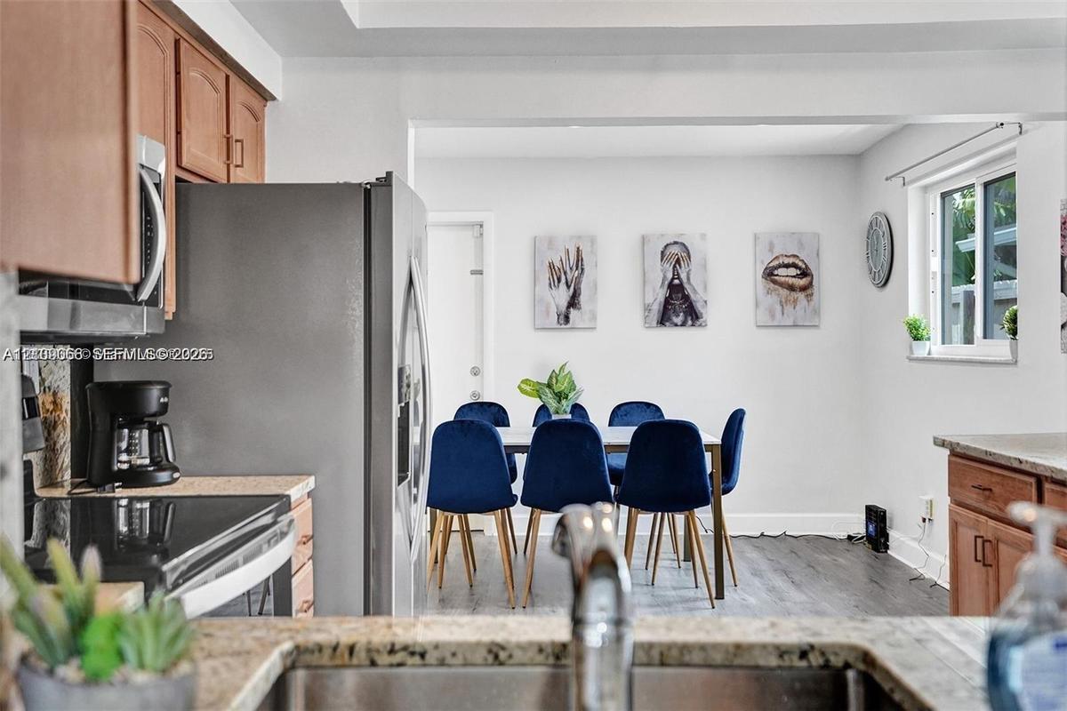 Kitchen featuring wood-finish cabinetry, stainless steel refrigerator, stone countertops, and wood-finish flooring