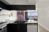 Kitchen featuring matte black cabinetry with brushed gold hardware, stone countertops, double basin undermount sink with a gooseneck faucet, stainless