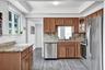 Kitchen featuring wood cabinetry, stone countertops, stainless steel appliances, and wood-finish flooring