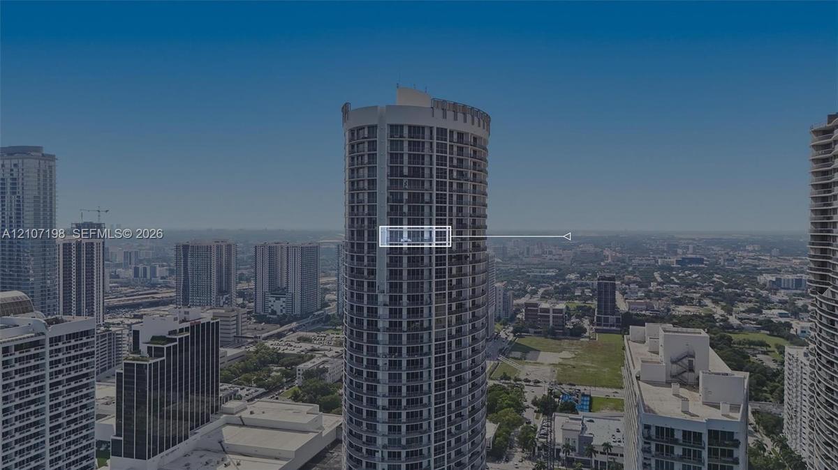 High-rise residential tower featuring a cylindrical glass facade, exterior balconies, and reinforced concrete structural elements