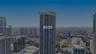 High-rise residential tower featuring a cylindrical glass facade, exterior balconies, and reinforced concrete structural elements