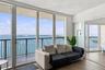 Floor-to-ceiling windows, wood-finish flooring, sliding glass door access to a private balcony, and metal balcony railing