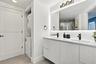 Double-vanity cabinet with fluted detailing, integrated solid-surface countertop, matte black fixtures, full-width mirror with backlighting, and built