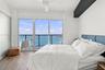 Floor-to-ceiling windows, wood-finish flooring, private balcony with metal railing, ceiling fan, and frosted glass door