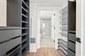Custom reach-in closet featuring dark-finish built-in cabinetry, integrated drawer banks, adjustable open shelving, and metal wire rack storage with w