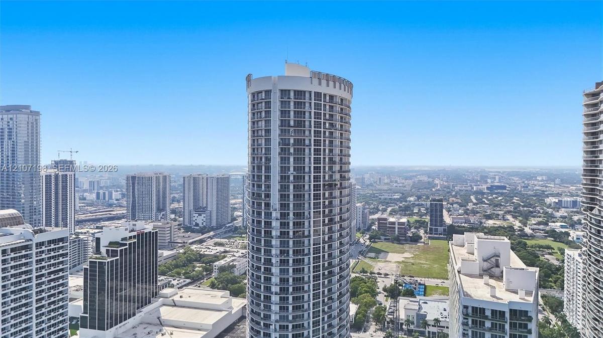 High-rise residential tower featuring a cylindrical glass and concrete facade with private balconies