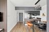 Interior featuring wood-finish flooring, vertical slat wall paneling, matte black cabinetry, a peninsula with dark-toned counters, and a modern multi-