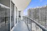 Covered balcony featuring concrete flooring, a curved metal railing, and floor-to-ceiling glass panel doors