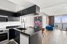 Matte black cabinetry, stone-finish countertops, stainless steel appliance suite, wood-finish flooring, and a private balcony with water backdrop