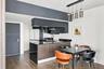 Kitchen featuring matte black cabinetry, contrasting dark stone countertops, a fluted-panel island, wood-finish flooring, and a multi-pendant light fi