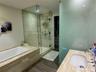 Bathroom featuring a soaking tub with stone-finish surround, glass-enclosed shower with adjustable rainfall showerhead, stone-finish vanity countertop