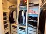 Custom walk-in closet featuring white built-in shelving, hanging rods, and integrated storage drawers