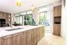 Kitchen island featuring a stone-surface countertop, integrated under-mount sink, wood-finish cabinetry, floor-to-ceiling glass sliding doors, and pen