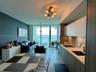 Kitchen featuring flat-panel cabinetry, light-toned countertops, tile backsplash, and floor-to-ceiling glass doors opening to a balcony
