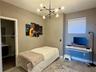 Modern multi-arm sputnik-style chandelier, wall-mounted floating desk, stone-finish tile flooring, and roller shade window treatment