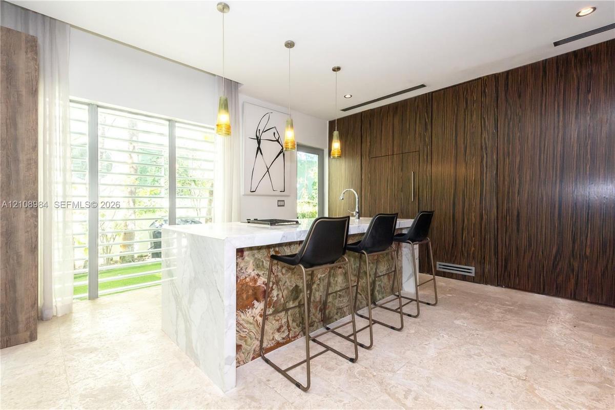 Kitchen island featuring a waterfall stone countertop with a contrasting decorative stone base, floor-to-ceiling wood-finish paneling, stone flooring,