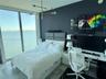 Floor-to-ceiling windows, porcelain tile flooring, modern metal multi-arm chandelier, and accent wall