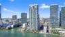 High-rise residential tower featuring a glass-facade exterior, waterfront location, and urban landscape surroundings