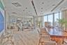Open-concept living space featuring floor-to-ceiling windows, recessed architectural lighting, wood-finish flooring, and a coffered ceiling design