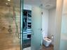 Walk-in shower with stone-tile surround, chrome wall-mounted fixtures, and glass door