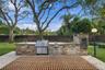 Outdoor kitchen featuring stacked stone cladding, stainless steel grill and storage cabinetry, built-in smoker, and integrated sink