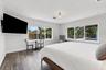 Neutral-toned interior featuring wood-finish flooring, dual large-scale windows with natural light, a semi-flush mount ceiling fixture, and crown mold