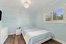 Room featuring wood-finish flooring, plantation shutters, and a decorative chandelier