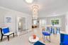 Open-concept interior featuring large-format tile flooring, a multi-tiered crystal-style chandelier, decorative crown molding, and a built-in stone-to