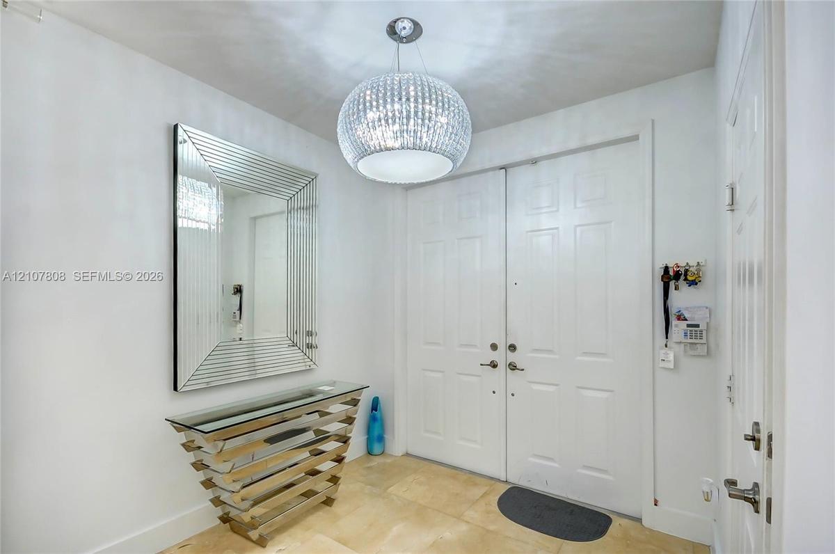 Foyer entry featuring double doors, stone tile flooring, and a spherical crystal pendant light fixture
