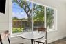 Large-scale picture window with white trim, wood-finish flooring, and backyard access featuring a wood privacy fence and mature landscaping