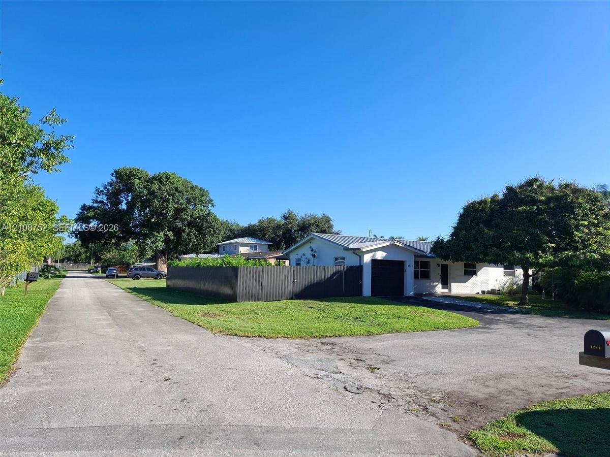Single-story exterior featuring a metal roof, an attached garage, and a fenced-in side yard situated on a corner lot with paved driveway access