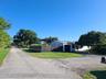 Single-story exterior featuring a metal roof, an attached garage, and a fenced-in side yard situated on a corner lot with paved driveway access